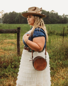 Chocolate leather Cowboy Stitch Canteen Bag with floral tooling, Buckstitch accents, and removable strap.